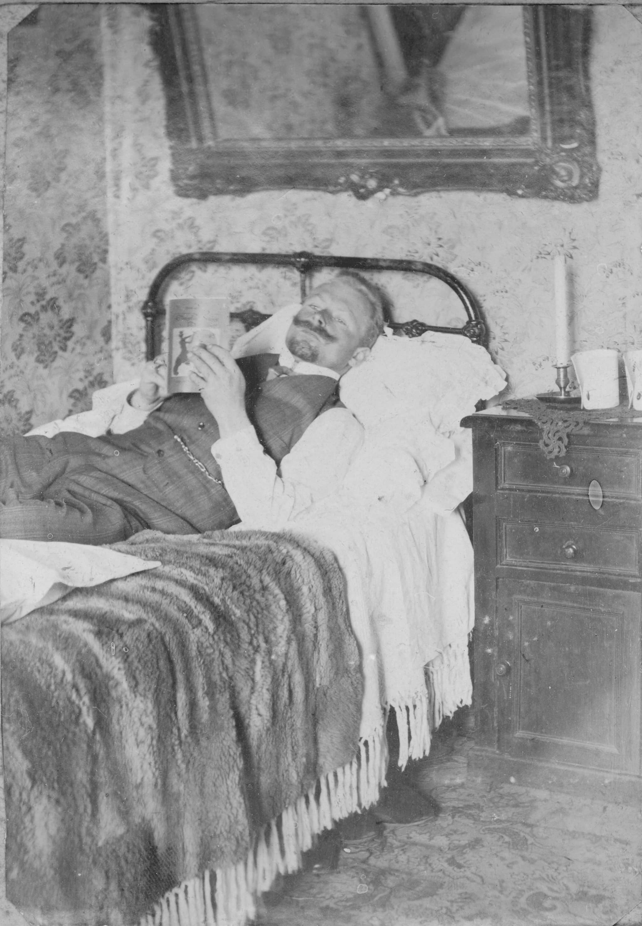 Hombre leyendo en una cama, ca. 1900